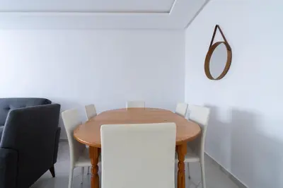 a dining room with a wooden table and chairs at Appartement Moderne avec Piscine in Bouznika