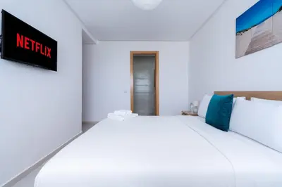 a white bed in a room with a sign on the wall at Appartement Moderne avec Piscine in Bouznika