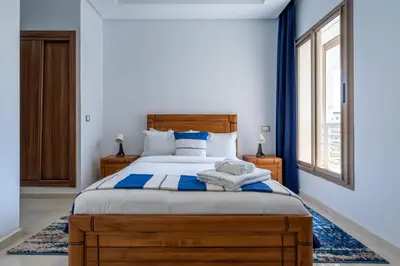 a bedroom with a large wooden bed with blue accents at Détente en Famille, Piscine, Plage à Proximité in Bouznika