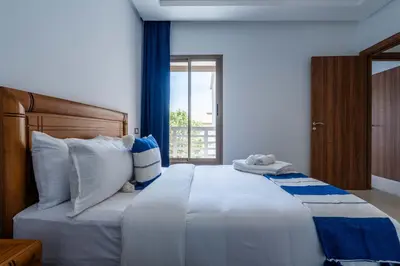 a bedroom with a large white bed with a window at Détente en Famille, Piscine, Plage à Proximité in Bouznika