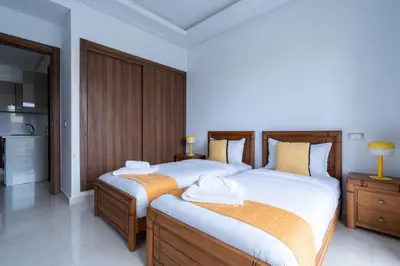 a bedroom with two beds and a kitchen at Détente en Famille, Piscine, Plage à Proximité in Bouznika
