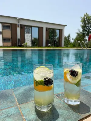 two glasses of drinks sitting next to a swimming pool at Farm - Private pool - Games - Nature in El Jadida