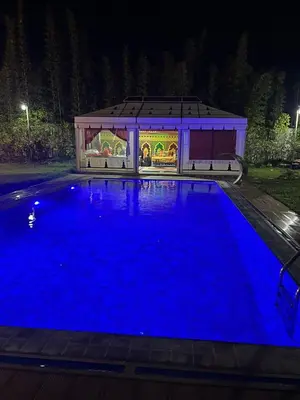 a large blue swimming pool at night with a stage at Farm - Private pool - Games - Nature in El Jadida