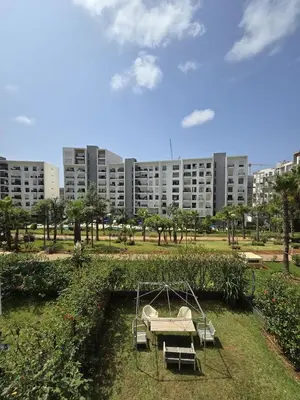 a swing in a park in front of a building at Elegant & Spacious Apartment in Prestigia in Rabat