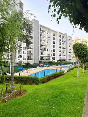 a large apartment building with a swimming pool in a park at Elegant & Spacious Apartment in Prestigia in Rabat