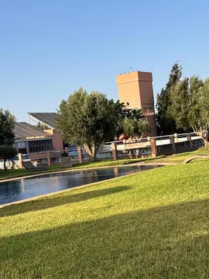 a park with a pond in front of a building at Farm with villa and pool in Settat