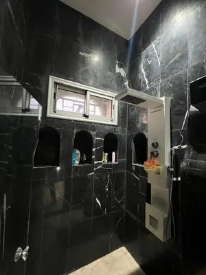 a bathroom with a black tiled shower with a window at Farm with villa and pool in Settat