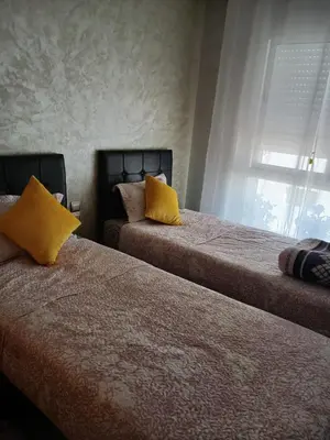 two beds with yellow pillows in a bedroom at Appartement bouznika in Bouznika