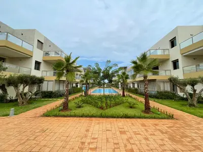 a courtyard with palm trees in front of a building at Les Sables de Sidi Rahal - Blue Beach in Sidi Rahal