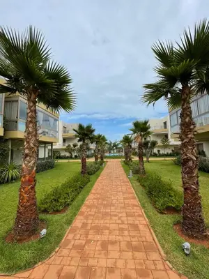 a brick pathway with palm trees in front of a building at Les Sables de Sidi Rahal - Blue Beach in Sidi Rahal
