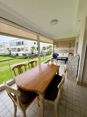 a wooden table and chairs in a room with a large window at OlaBlanca2, appartement avec terrasse et vue sur piscine in Sidi Rahal