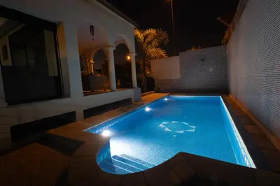 a swimming pool in the middle of a house at night at Villa avec piscine et sauna 8 chambres proche commodité et Casa Finance City in Casablanca