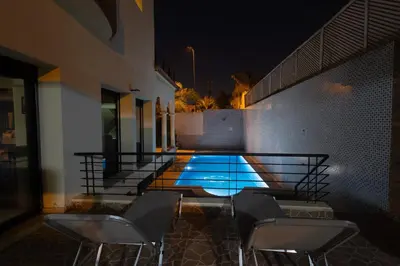 a swimming pool with four chairs next to a building at Villa avec piscine et sauna 8 chambres proche commodité et Casa Finance City in Casablanca