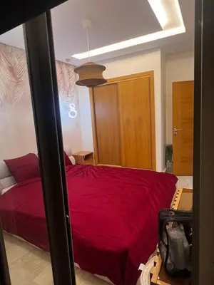 a bedroom with a red bed and a wooden cabinet at Appartement de luxe avec parking gratuit à Casablanca, Vue & Confort in Aïn Sebaa