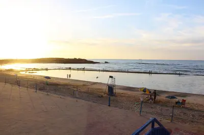 a view of a beach with the sun setting at Palm beach in Mansouria in O Ben Slimane