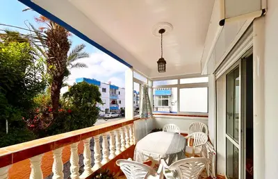 a balcony with white chairs and a table at Palm beach in Mansouria in O Ben Slimane
