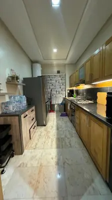 a large kitchen with wooden cabinets and a marble floor at Jnane californie in Casablanca