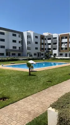a palm tree in front of a large building at Luxueux Appartement Familial à Harhoura, Rabat Piscine & Plage à pied in Temara
