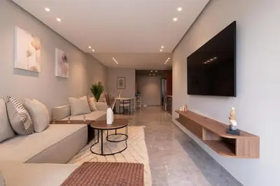 a living room with a couch and a tv on a wall at Studio 1BR Near CFC - 5 Stars Experience in LʼOasis
