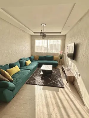 a living room with a green couch and a tv at Sunny 2-Bedroom Apartment with Pool for a Great Stay in Mohammedia