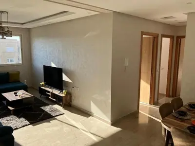 a living room with a blue couch and a tv at Sunny 2-Bedroom Apartment with Pool for a Great Stay in Mohammedia