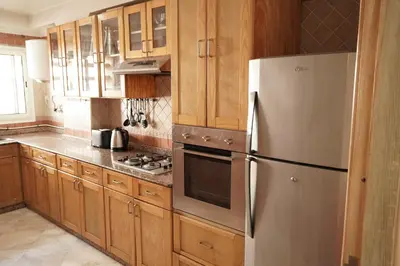 a kitchen with wooden cabinets and a stainless steel refrigerator at Cosy Loft - 2 Bedrooms & Parking - Agdal Center in Rabat