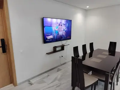 a dining room with a table and a television on a wall at Beautiful apartment 2 bedrooms living room aéroport mohamed 5 nouaceur Casablanca in Casablanca