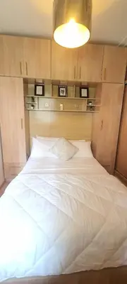 a large white bed in a room with a light at Appartement avec Piscine à Tamaris, Confort, Vue Jardin et Plages à Proximité in Tamaris