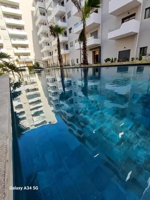 a swimming pool in front of a building at Très beau studio Océan Park in Aïn Harrouda