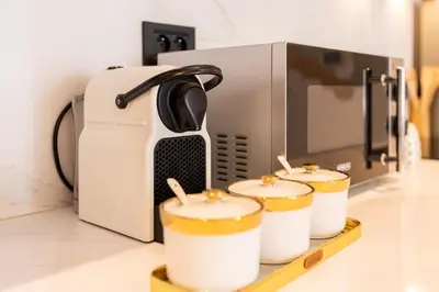 a coffeemaker with four coffee cups on a tray next to a microwave at Chic blue studio au cœur deCasablanca in Casablanca