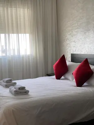 a bedroom with a bed with red pillows and a window at Appartement Spacieux & Moderne, 2 min Gare, 10 min Plage, Parking Gratuit in Casablanca