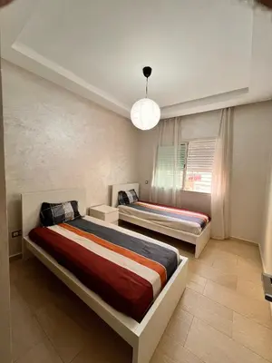 a bedroom with two beds and a chandelier at Horizon Relax in Mohammedia