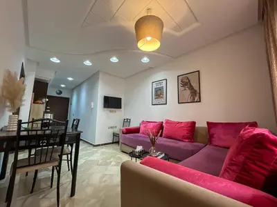 a living room with pink couches and a dining room at Central Studio Casablanca in Casablanca