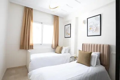 two beds in a room with white walls and a window at Appartement Luxueux pour Famille - Quartier Abdelmoumen in Casablanca