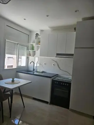 a kitchen with white cabinets and a sink and a table at Apartamento Bonito in Rabat