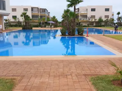 a large blue swimming pool in front of a building at Résidence blue beach Sidi rahal in Sidi Rahal