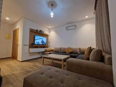 a living room with a couch and a tv at Résidence blue beach Sidi rahal in Sidi Rahal
