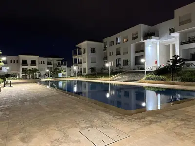 a swimming pool in front of a building at night at Beach flat with pool at Al Mansouria in O Ben Slimane