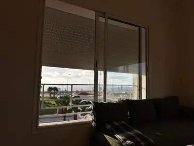 a living room with a large window with a couch at Beach flat with pool at Al Mansouria in O Ben Slimane