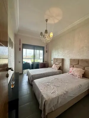 a bedroom with two beds and a chandelier at Appartement Blanca Beach in Sidi Rahal