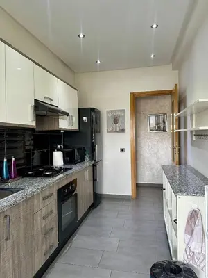 a large kitchen with white cabinets and black appliances at Appartement Blanca Beach in Sidi Rahal