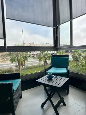 a table and chairs in a room with windows at Appartement Blanca Beach in Sidi Rahal