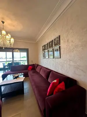 a living room with a red couch and a chandelier at Appartement Blanca Beach in Sidi Rahal