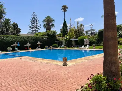 a large swimming pool with a tree in the foreground at Beach palace 1 between sea pool and city center in Mohammedia