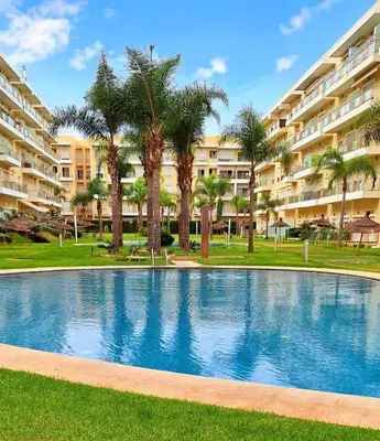 a swimming pool in front of a large apartment building at LES JARDINS DE BOUZNIKA PREMIUm in Bouznika