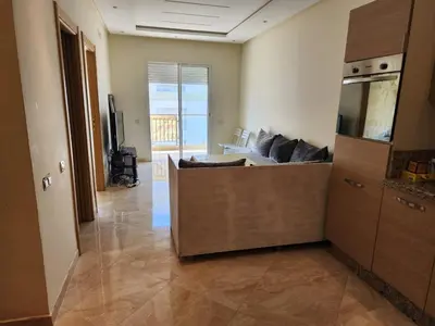 a living room with a couch and a television at LES JARDINS DE BOUZNIKA PREMIUm in Bouznika