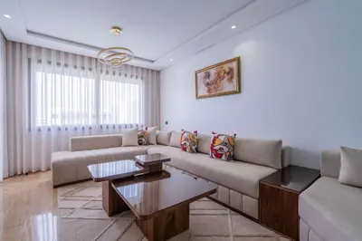 a living room with a couch and a table at Appartement avec Piscine dans Résidence Privée in Dar Bouazza