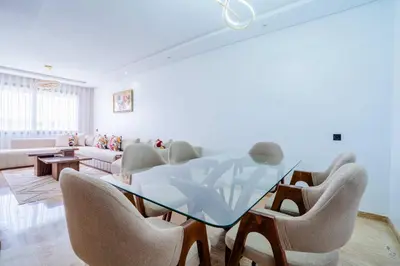 a dining room with a glass table and chairs at Appartement avec Piscine dans Résidence Privée in Dar Bouazza