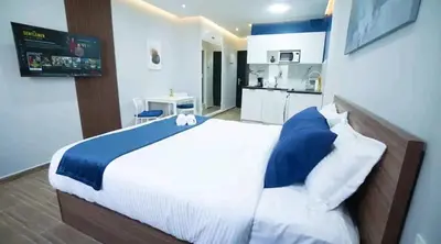a bedroom with a large bed and a kitchen at Luxe Bleu Studio Rabat in Rabat