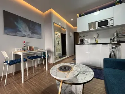 a kitchen with white cabinets and a table in a room at Luxe Bleu Studio Rabat in Rabat